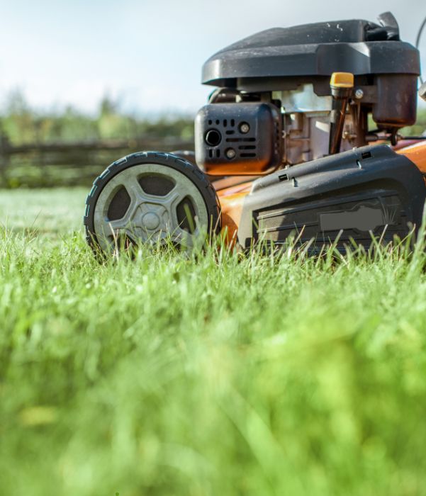 An orange lawn mower positioned on a lush green field, showcasing vibrant colors and a well-maintained landscape.