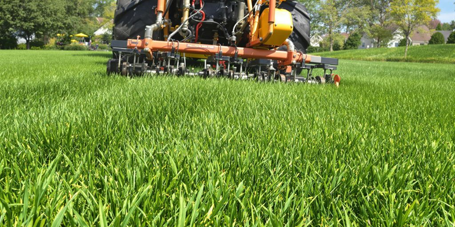  A tractor plows through a lush green field of grass, showcasing agricultural activity in a rural landscape.